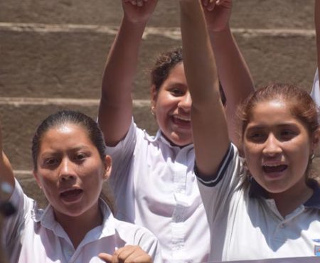 Impulsando talentos y derechos humanos de niñas en El Salvador. Imagen de niñas alzando las manos.